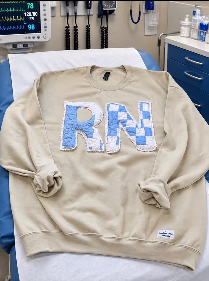 Sand sweatshirt with the letters RN appliquéd from blue and white patchwork quilt fabric, edged with white ruffled eyelet trim
