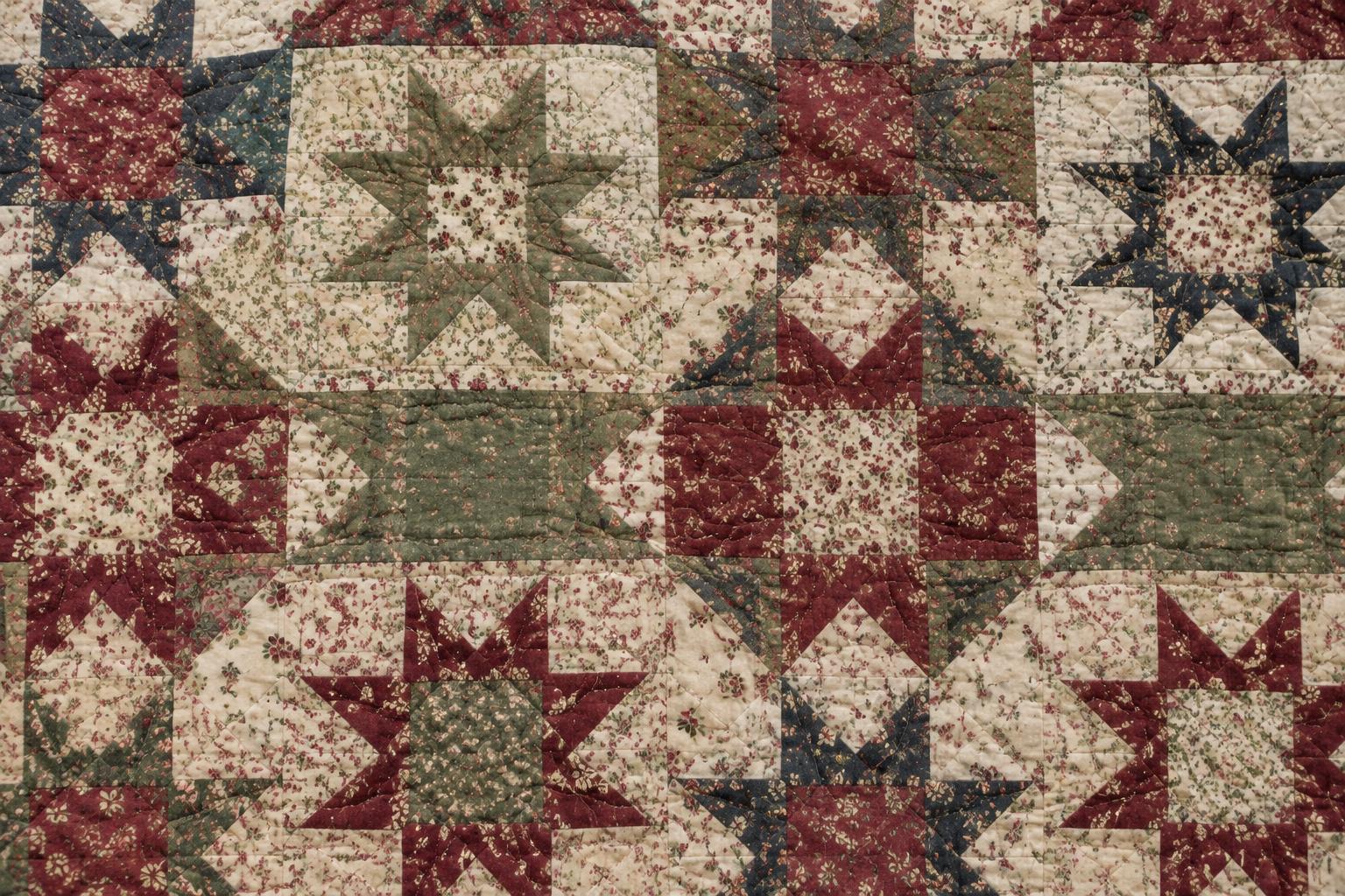 Illustrative antique star quilt with burgundy, sage, and navy floral patchwork